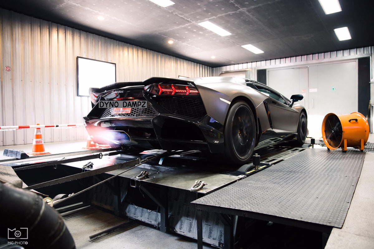 Matte black Lamborghini Aventador with glowing exhausts strapped on Dynocom AWD 8000 dynamometer at Dyno Dampz