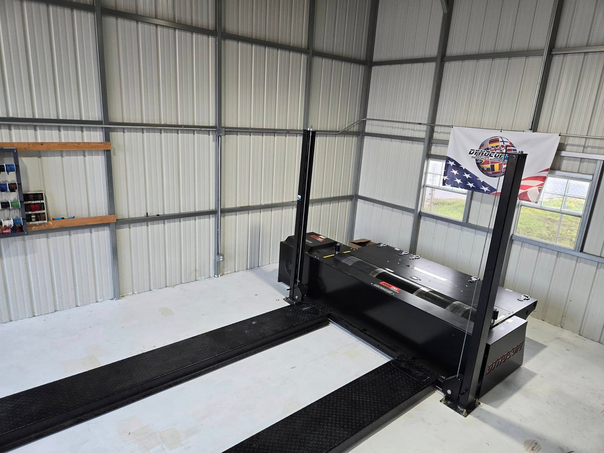Dynocom 2WD 8000 Series chassis dynamometer installed in metal shop building with Dynocom Racing banner