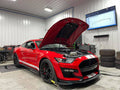 Red Shelby GT500 with hood open on Dynocom 21,000 Series dyno with power curve displayed on monitor