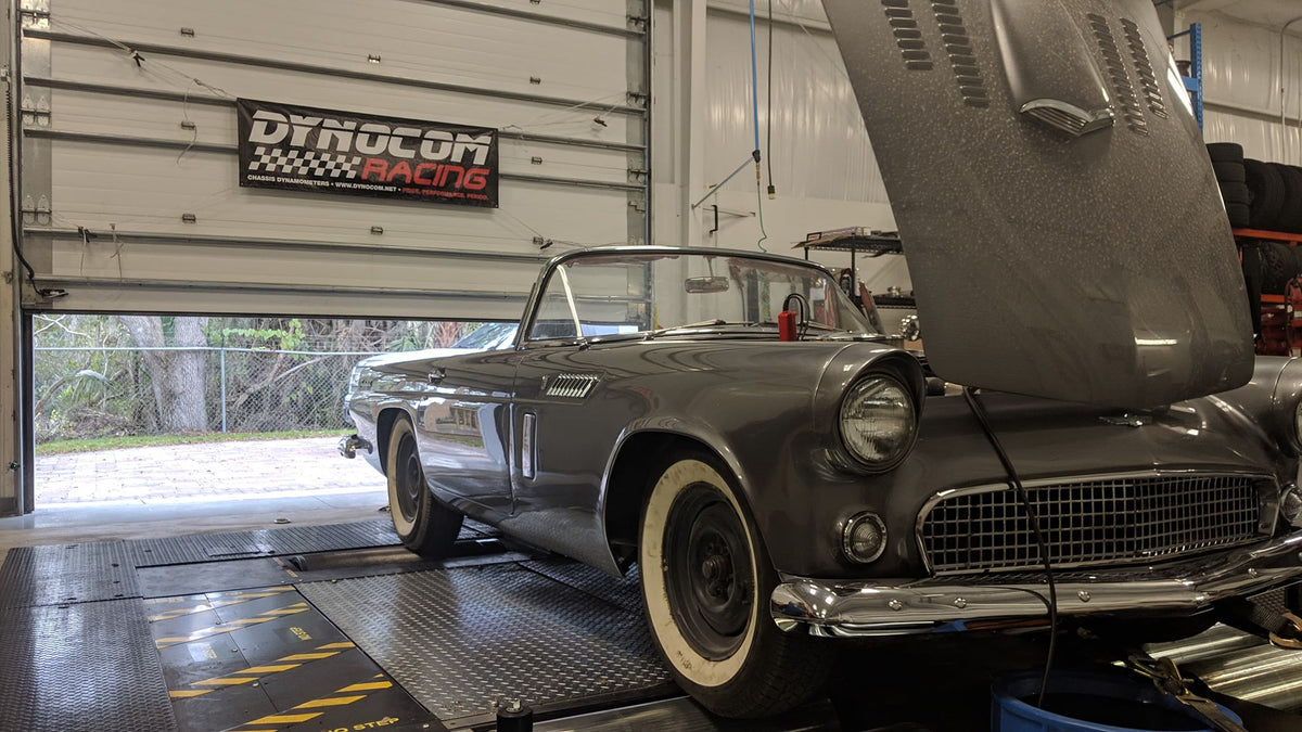 Classic grey Ford Thunderbird convertible with hood open on Dynocom AWD 15,000 GDFX dyno under Dynocom Racing banner