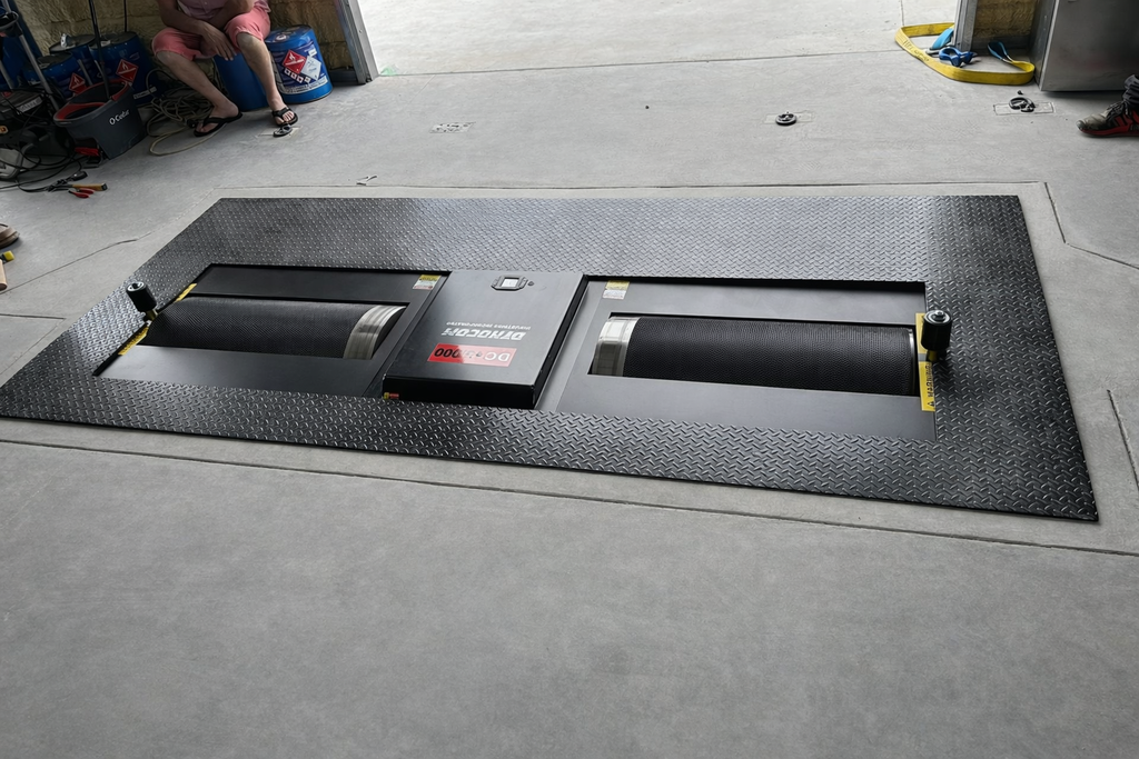 Dynocom DC-3000 pit-mount chassis dynamometer installed in garage floor with diamond plate surround