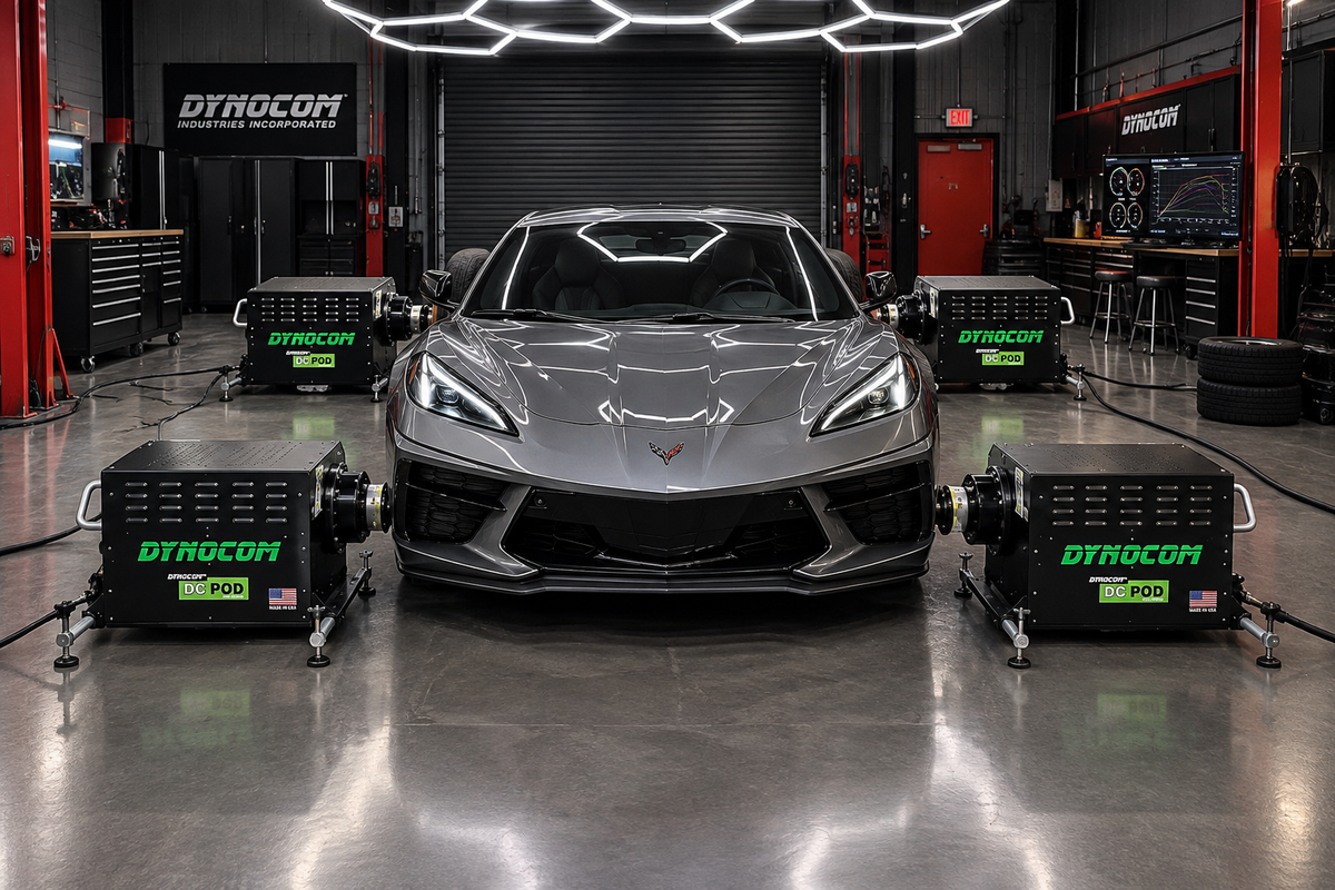 Grey C8 Chevrolet Corvette surrounded by four Dynocom DC POD AWD 2000 hub dynamometer units in Dynocom Industries showroom