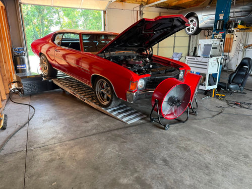 Red classic Chevelle muscle car on Dynocom dyno with hood open in performance shop
