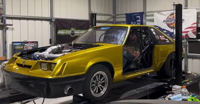 Gold Fox Body Mustang with turbo on Dynocom dyno making a pull inside performance shop