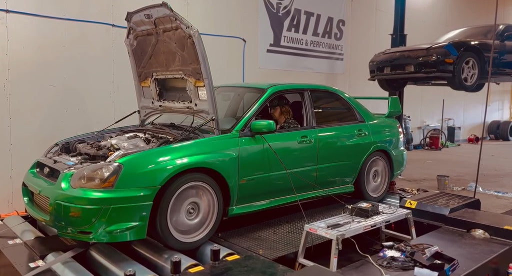 Green Subaru WRX STI with hood open on Dynocom AWD dyno at Atlas Tuning and Performance shop
