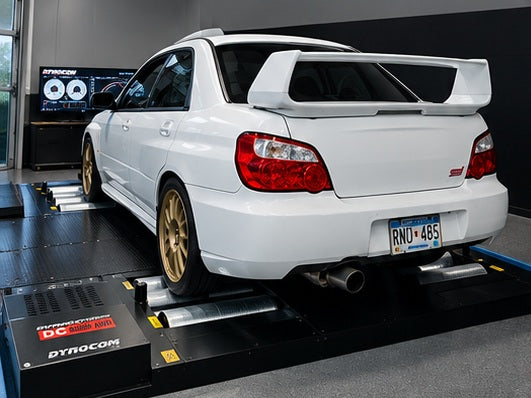White Subaru WRX STI with gold wheels strapped on Dynocom DC 6000 AWD dynamometer